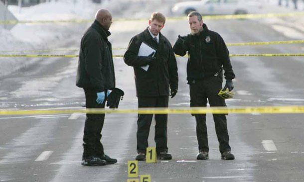 Investigators stand near a crime scene in which a Denver Broncos cornerback was shot and killed. Two other people in the vehicle were also shot in what police are calling a drive-by shooting.<br /> (AP/Ed Andrieski)