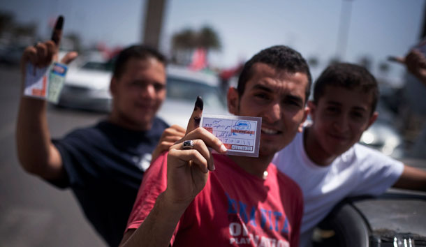 Libyan men hold their election ID cards while celebrating election day in Tripoli, Libya. (AP/Manu Brabo)