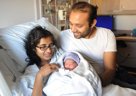 Rabita Sarkar and her husband Aditya Saurabh pose with their newborn baby boy at St. Luke's-Roosevelt Hospital in New York.The United States is the only industrialized nation that does not guarantee workers paid time off to provide care to a new child. (AP/ Louis Lanzano)