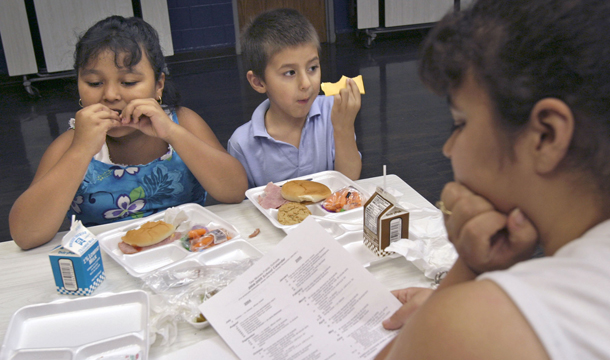 Angelica Segovia, 7, left, and her brother, Santiago Fernandez, 5, eat lunch with their mother, Juanita Fernandez, right, at King Elementary School in Des Moines, Iowa. The school offers free lunches to neighborhood children as part of the federal government's free and reduced-price lunch program for low-income children. (AP/J. Mark Kegans)