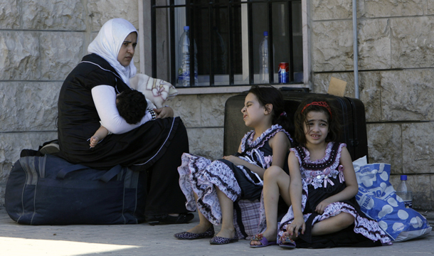A Syrian woman sits with her children outside the Lebanese immigration office at the Masnaa border post shortly after crossing from Syria to Majdal Anjar, Lebanon, Monday, July 23, 2012. (AP/Bilal Hussein)