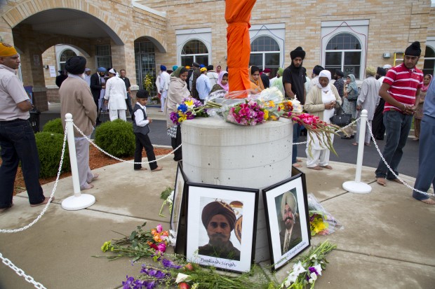 People walk around a flag pole memorial outside the Sikh Temple of Wisconsin in Oak Creek, Wisconsin, the site of a hate-fueled, violent attack that left six members of the Sikh community dead. (AP/ Jeffrey Phelps)