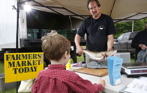Glen Libby shows a cod fish to a youngster at the Port Clyde Fresh Catch stand at the Farmer's Market in Rockland, Maine. (AP/Robert F. Bukaty)