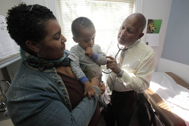 Dr. Michael Lenoir, right, examines Dante Jones, 2, being held by his mother Daaiyah Shabazz in Lenoir's offices in Oakland, California. (AP/Marcio Jose Sanchez)