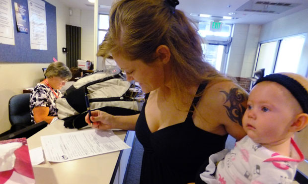 Laura Fritz, 27, holds her daughter and fills out a form at the Jefferson Action Center, an assistance center in the Denver suburb of Lakewood. (AP/Kristen Wyatt)