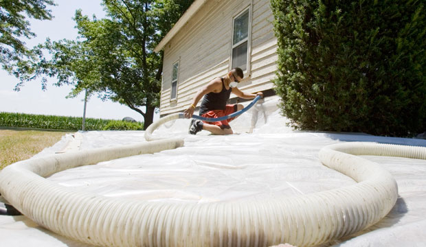 Edwin Aguilar pumps insulation material into a wall during weatherization work on a home in Grafton, Nebraska. (AP/Nati Harnik)