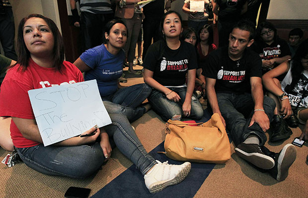 Yadira Garcia, left, of the Arizona Dream Act Coalition, holds up a sign in protest as she joins young immigrants as they sit in the waiting area of Gov. Jan Brewer's (R-AZ) office on Thursday, August 16, 2012, in Phoenix. (AP/Ross D. Franklin)