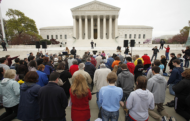 Members of Christian faith organizations kneel in prayer in front of the U.S. Supreme Court in Washington as part of 