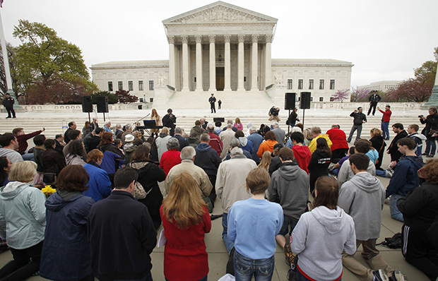 Members of Christian faith organizations kneel in prayer in front of the U.S. Supreme Court in Washington as part of