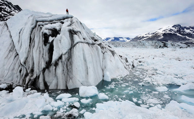 A hiker surveys the damage from climate change atop an iceberg in Alaska. Correcting climate change used to be a bipartisan effort, but recently has become more partisan, causing faith groups to get involved. (AP/James Balog)