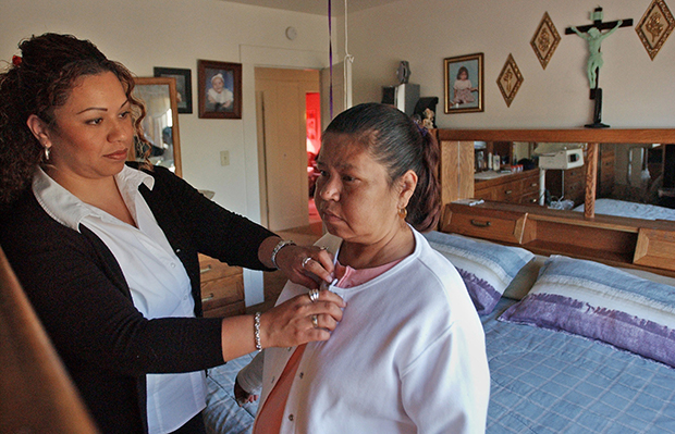 Elizabeth Gomez, left, assists her mother, Virginia Falcon, at home in Oakland, California. (AP/Ben Margot)