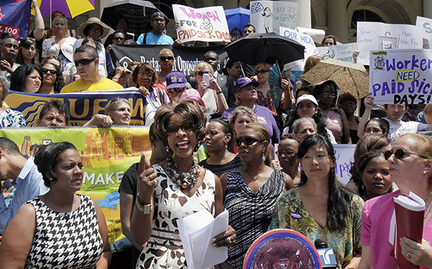 Marjorie Hill, second left, CEO of the Gay Men's Health Crisis, addresses the Women for Paid Sick Days rally on the steps of New York's City Hall, Wednesday, July 18, 2012. The lack of universal paid sick days exacerbates the vulnerabilities many gay and transgender people experience in the workplace. (AP/Richard Drew)