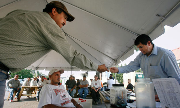 Francisco Cerna shows his ticket number to Angel Morales, a coordinator with the Herndon Official Workers Center, in Herndon, Virginia. Latinos are more likely to be part-time employees, meaning they are less likely to have access to paid leave and workplace flexibility. (AP/Jacquelyn Martin)