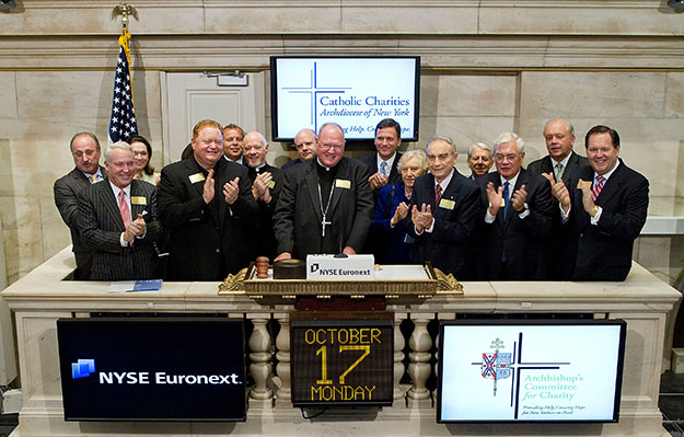Archbishop of New York Timothy M. Dolan, center, rings the opening bell at the New York Stock Exchange on Monday, October 17, 2011, in New York. A Catholic Charities press statement said Dolan met with 