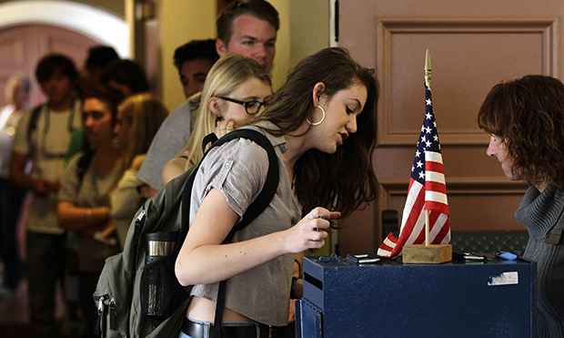 College student Cortney Ratashak, 18, of Littleton, Colorado, talks over paperwork with an electoral official before voting in the general election, at a polling station serving the local student population on the campus of the University of Colorado, in Boulder, Colorado, Tuesday, November 6, 2012. (AP/Brennan Linsley)