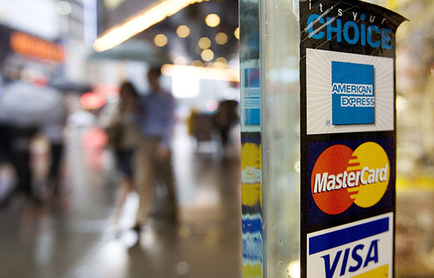 Signs for American Express, MasterCard, and Visa credit cards are shown on a New York store's door in 2007. (AP/Mark Lennihan)