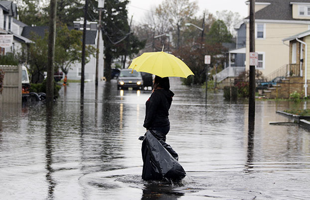 Lisa Torres walks along a flooded street to check the flood damage at her hair salon in the wake of superstorm Sandy on Tuesday, October 30, 2012, in Little Ferry, New Jersey. Sandy arrived along the East Coast and morphed into a huge and problematic system, putting more than 7.5 million homes and businesses in the dark and causing a number of deaths. (AP/Mike Groll)