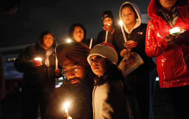 Eknoor Kaur, 3, stands with her father, Guramril Singh, during a candlelight vigil outside Newtown High School before an interfaith vigil with President Barack Obama, Sunday, December 16, 2012, in Newtown, Connecticut. (AP/Jason DeCrow)