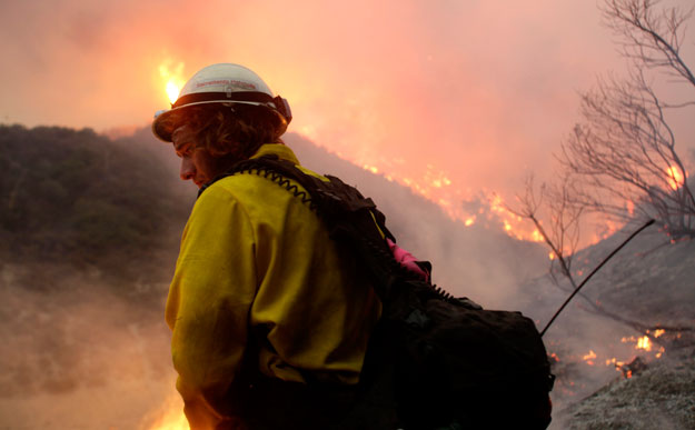 Wildland firefighter Sterling Rel watches a fire line threatening houses in the La Crescenta section of Glendale, California, in 2009. One possible outcome of budget cuts in 2013 is fewer wildland firefighters, which means less protection in the event of a wildfire. (AP/LM Otero)