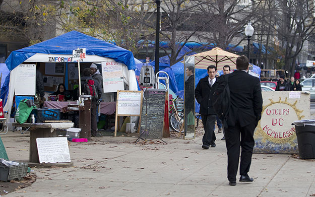 Occupy DC protesters watch morning commuters walk through McPherson Square in Washington on Monday, December 5, 2011. The income gap between the rich and everyone else is large and getting larger, while middle-class incomes stagnate. This has raised concerns that the nation's middle class isn't sharing in economic growth as it has in the past, and sparked the Wall Street protests that spread to other cities in the country. (AP/Evan Vucci)