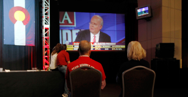 A couple watches Fox News commentator Karl Rove on a big-screen television during a Republican Party election night gathering on November 6, 2012. (AP/David Zalubowski)