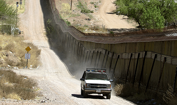 A U.S. Border Patrol agent patrols along the fence line of the U.S.-Mexico border in Nogales, Arizona. (AP/Khampha Bouaphanh)