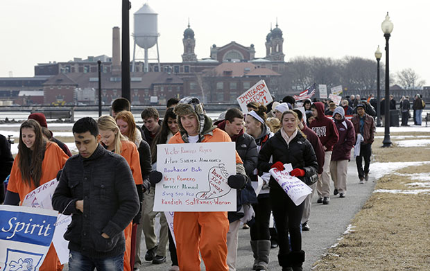 With Ellis Island in the background, a group of immigrant rights advocates march on Wednesday, February 13, 2013, in Liberty State Park, Jersey City, New Jersey. (AP/Mel Evans)