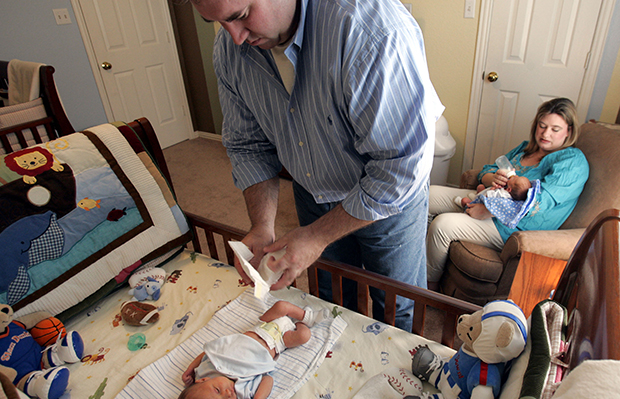 Tim Waddill changes Chase, his newborn twin son's diaper, left, as Stephanie Waddill, back, gives a bottle to their other twin boy, Connor, at their home in Irving, Texas, Friday, June 16, 2006. (AP/Donna McWilliam)