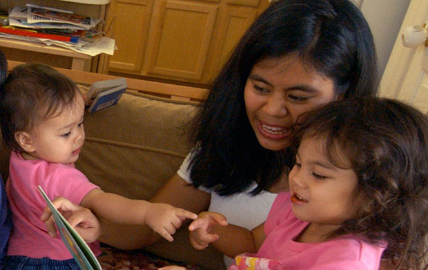 Maria Prince reads to her children Monica, 1 year old, and Olivia, 3 years old, in her home in Crofton, Maryland. (AP/Jacqueline Malonson)