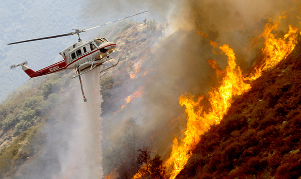 A Los Angeles County Firefighter helicopter drops water on a wildfire burning through 3,600 acres of the Angeles National Forest on Tuesday, September 4, 2012, near Glendora, California. (AP/Nick Ut)