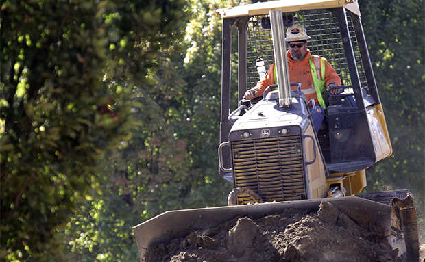 A worker levels dirt for a light rail bridge construction project over the Willamette River in Portland, Oregon, Friday, October 5, 2012. (AP)