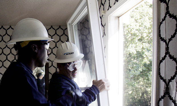 Richard Hucks, winterization project manager for South Carolina Electric & Gas Company, gets help from Demetrius Rumph, left, as they install energy-efficient windows in the home of Melba Jeffcoat in West Columbia, South Carolina. (AP/Mary Ann Chastain)