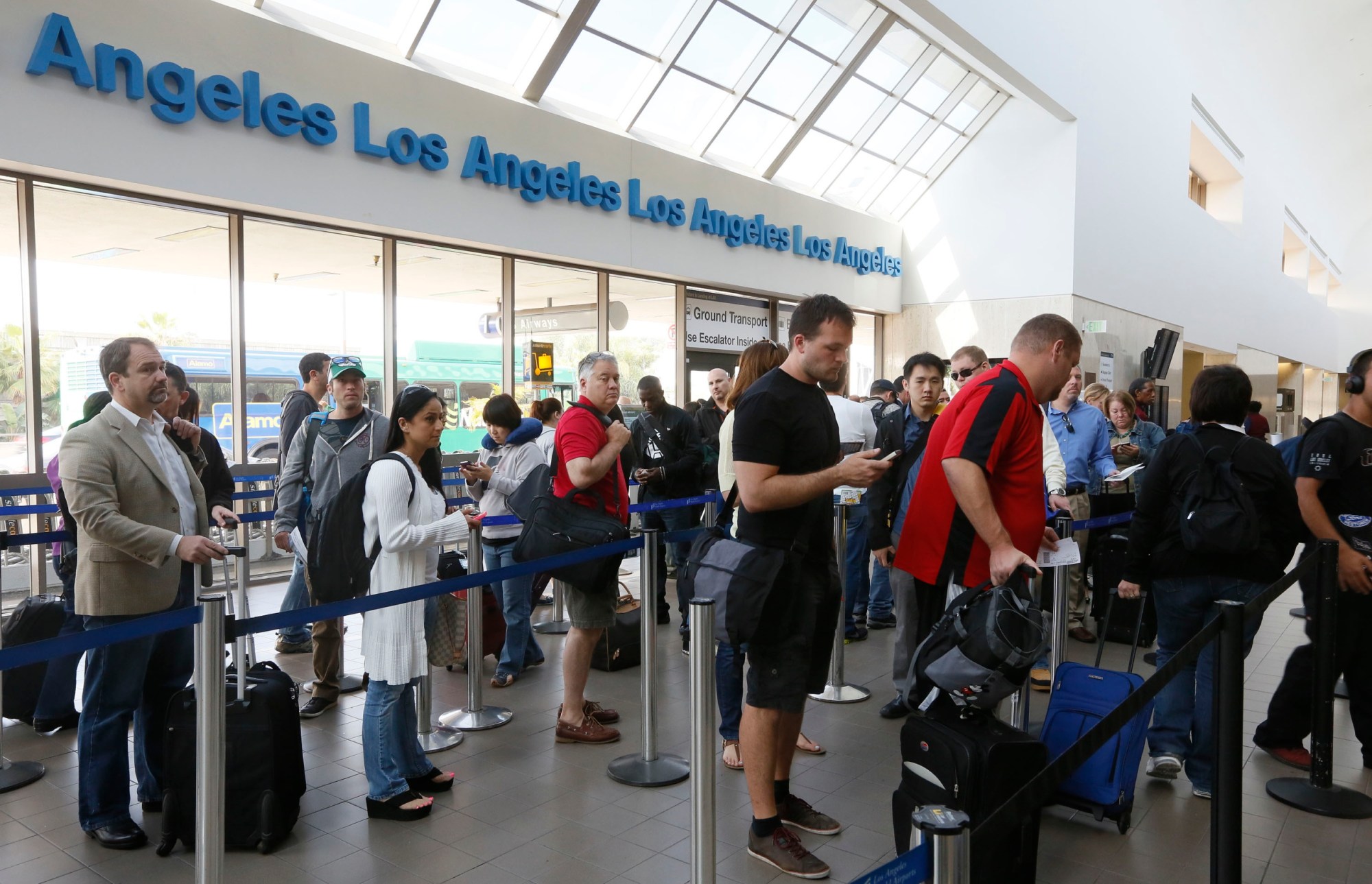 Travelers stand on line at the LAX International Airport in Los Angeles. It was a tough start to the week for many air travelers, as thousands of air traffic controllers were forced to take an unpaid day off because of federal budget cuts. (AP/Damian Dovarganes)