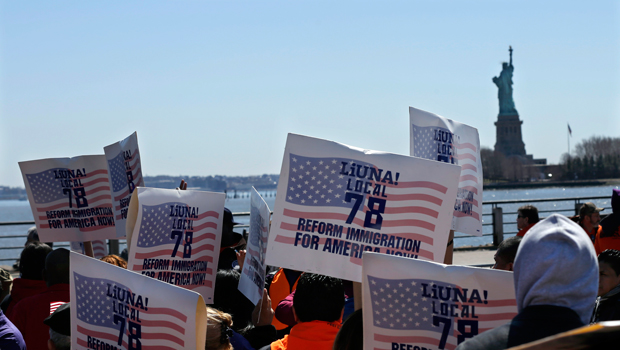 People look out at the Statue of Liberty while they hold signs Saturday, April 6, 2013, as members of New Jersey's congressional delegation as well as labor unions, religious leaders, immigrants, and immigration advocates rally at Liberty State Park in Jersey City, New Jersey. (AP/Mel Evans)