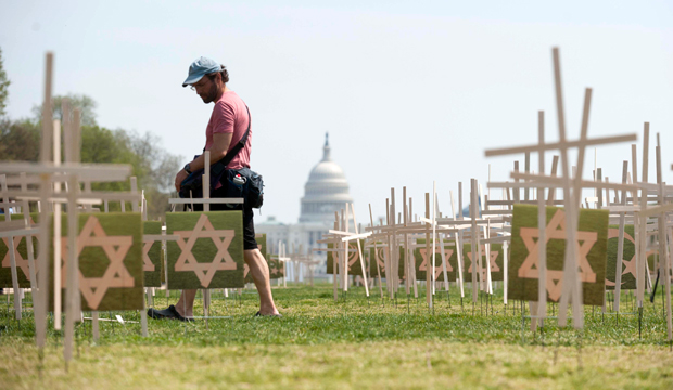 A man walks past thousands of grave markers erected in a mock cemetery to honor the victims of gun violence on the National Mall in Washington, Thursday, April 11, 2013. (AP/Kevin Wolf)