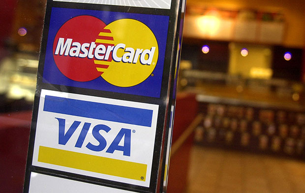Signs for MasterCard and Visa credit cards are shown at the entrance to a New York coffee shop in 2005. Millions of Americans are now turning to prepaid cards to help them manage their finances, and regulations need to evolve in order for cards to best serve consumers. (AP/Mark Lennihan)