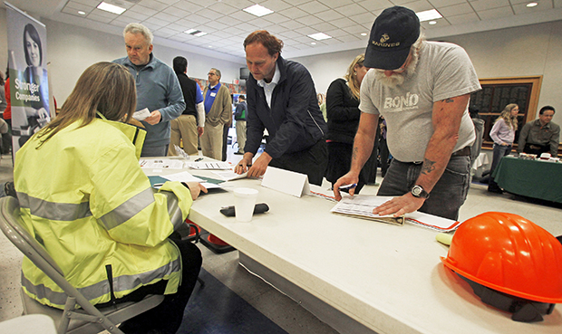 In this Thursday, April 3, 2013, photo, people fill out applications at the Green Mountain Flagging table at the 4th Annual Central Vermont Job Fair in Montpelier, Vermont. (AP/Toby Talbot)