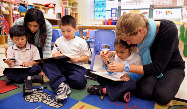 Pre-K teaching assistant Mirna Ayala, left, and teacher Laura Amling, right, work with their three-year-old students to draw an alphabet shape at Powell Elementary School in Washington. (AP/Cliff Owen)