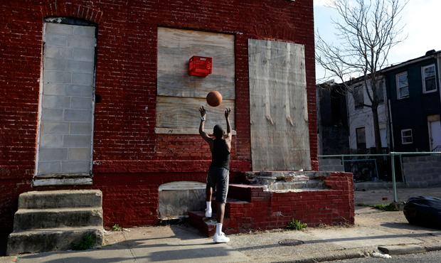 A boy shoots a basketball into a makeshift basket made from a milk crate and attached to a vacant row house in Baltimore, Maryland, April 8, 2013. (AP/Patrick Semansky)