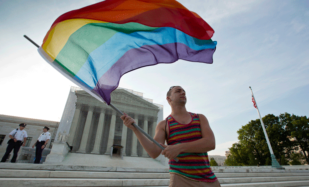 Gay rights advocate Vin Testa waves a rainbow flag in front of the Supreme Court at sun up on Wednesday, June 26, 2013. Today the Supreme Court repealed Section 3 of the Defense of Marriage Act. (AP/J. Scott Applewhite)