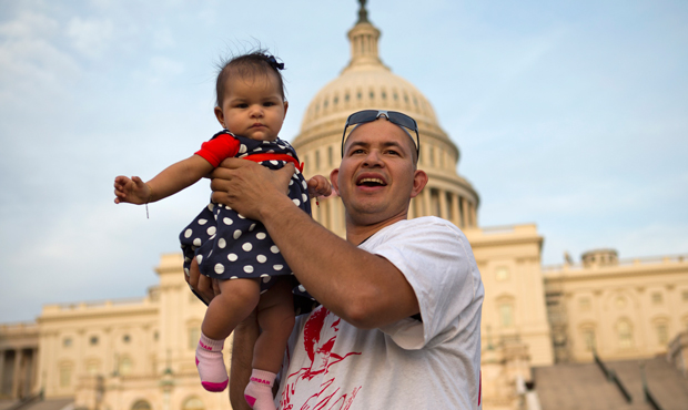 Edwin Munoz, who is originally from El Salvador, holds his daughter, Jocelyn, 5 months, up for a portrait at the end of the 