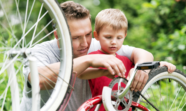 A father and son work on repairing their bike. (iStockphoto)