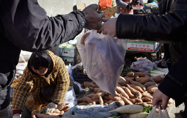A customer buys sweet potatoes at a morning market in Beijing, China, Thursday, January 24, 2008. (AP/Andy Wong)