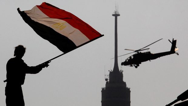 An opponent of Egypt's ousted President Mohamed Morsi waves a national flag as a military helicopter flies over Tahrir Square in Cairo, Egypt, Friday, July 5, 2013. (AP/Amr Nabil)