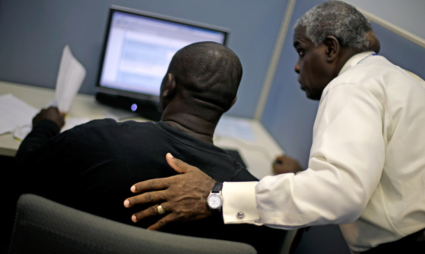 Employment Specialist Louis Holliday, right, helps an applicant file for unemployment at a Georgia Department of Labor career center, Thursday, July 18, 2013, in Atlanta, Georgia. (AP/David Goldman)