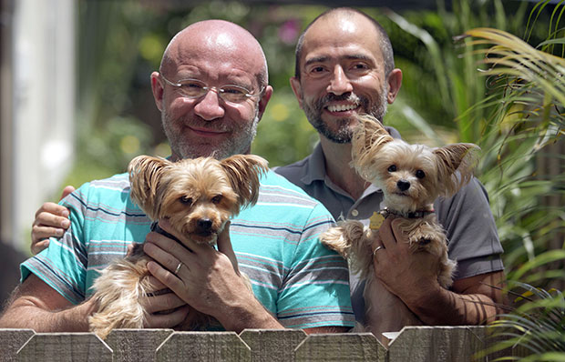 Julian Marsh, left, poses with his husband Tray Popov and their Yorkshire Terriers, Rosie, left, and Phoebe at their home, Monday, July 1, 2013, in Fort Lauderdale, Florida. Popov, who is a Bulgarian graduate student, and Marsh, a U.S. citizen, are the first gay couple in the nation to have their application for immigration benefits approved after the Supreme Court ruling on same-sex marriages, their lawyer says. (AP/Wilfredo Lee)