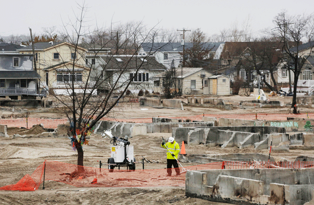 A worker with the U.S. Army Corps of Engineers rakes debris at the burn site in New York. Hundreds of homes burned to the ground during Superstorm Sandy, and the region is now dealing with a slow and frustrating, yet often hopeful, recovery. (AP/Mark Lennihan)