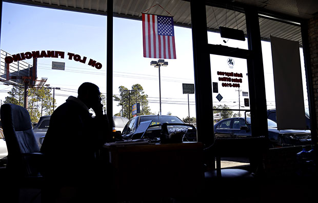 Salesman Donnie Alford talks on the phone in his office at Auto Express in Fayetteville, North Carolina, March 4, 2013. The auto and wheels business is located on Yadkin Road, near a main entrance to Fort Bragg military base. (AP/Gerry Broome)
