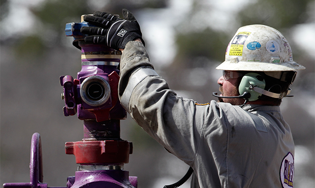 In this March 29, 2013, file photo, a worker switches well heads during a short pause in the water pumping phase, at the site of a natural gas hydraulic fracturing and extraction operation outside Rifle, in western Colorado. (AP/Brennan Linsley)