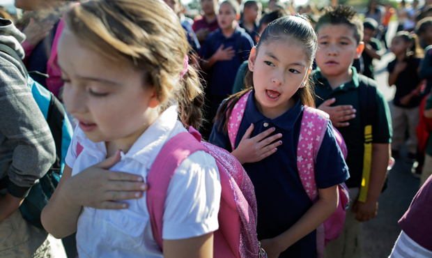 In this Thursday, May 23, 2013 photo, first grader Mariah Nevarez, center, says the pledge of allegiance with classmates before the start of school at Jay W. Jeffers Elementary School in Las Vegas. (AP/Julie Jacobson)